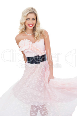 Pleased blonde model in pink dress posing shaking her dress