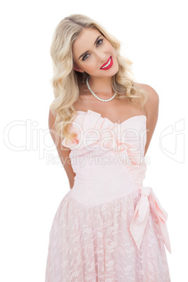 Happy blonde model in pink dress posing looking at camera