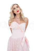 Thinking blonde model in pink dress posing looking away