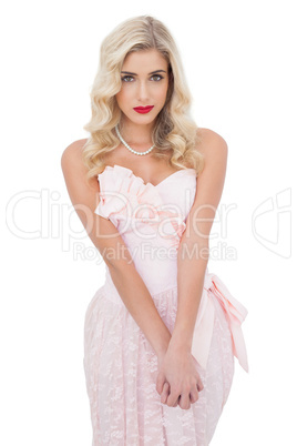 Unsmiling blonde model in pink dress posing looking at camera an