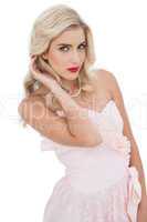 Unsmiling blonde model posing touching her hair