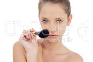 Concentrated brunette model pointing a brush at camera