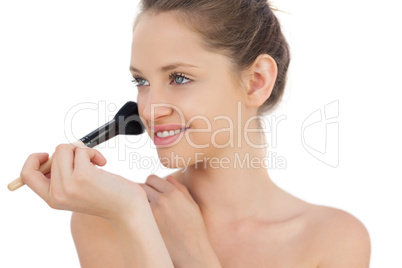 Pleased brunette model applying powder on her cheek