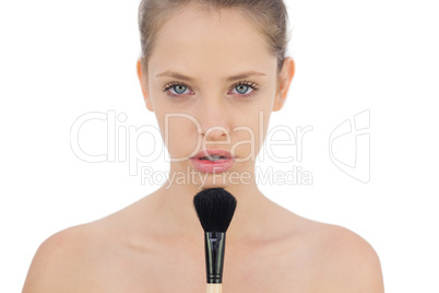 Unsmiling brunette model applying powder on her chin