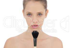 Unsmiling brunette model applying powder on her chin