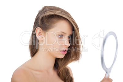Attentive brunette model looking herself in a mirror