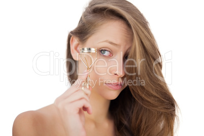 Puzzled brunette model looking an eyelash curler