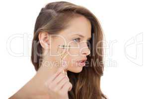 Unsmiling brunette model holding an eyelash curler