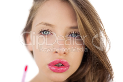 Concentrated brunette model applying pink gloss