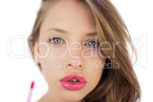 Concentrated brunette model applying pink gloss