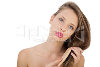 Thoughtful brunette model brushing her hair