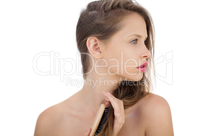 Pensive brunette model brushing her hair