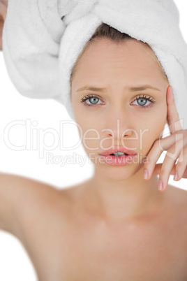 Unsmiling brunette drying her hair looking at camera