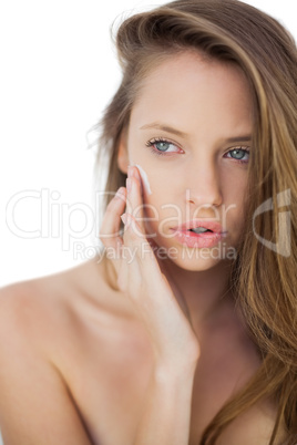 Cute brunette model rubbing her cheeks with cream