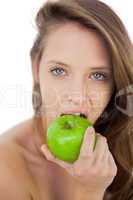 Unsmiling brunette model eating an apple