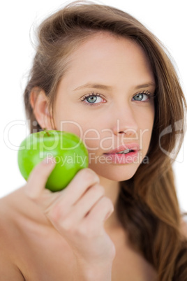 Unsmiling brunette model holding an apple