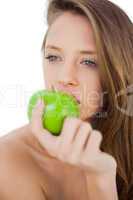 Thoughtful brunette model eating an apple