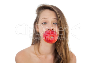 Concentrated brunette model holding an apple in her mouth