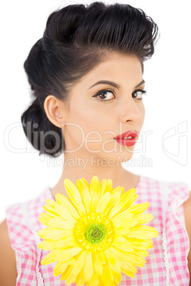 Thoughtful black hair model holding a flower and looking at came