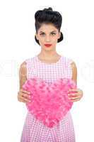 Serious black hair model holding a pink heart shaped pillow
