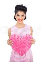 Delighted black hair model holding a pink heart shaped pillow