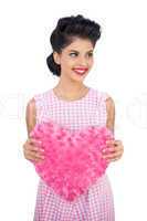 Cheerful black hair model holding a pink heart shaped pillow