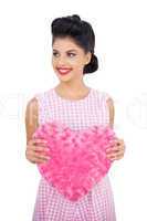 Joyful black hair model holding a pink heart shaped pillow