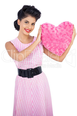 Playful black hair model holding a pink heart shaped pillow