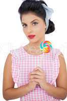 Thoughtful black hair model holding a colored lollipop