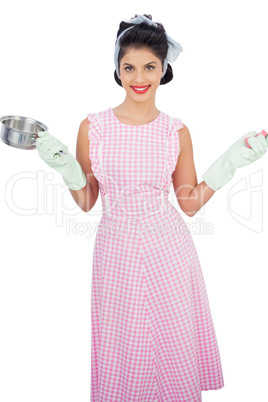 Pleased black hair model holding a pan and wearing rubber gloves
