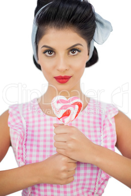 Charming black hair model holding a heart shaped lollipop