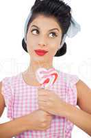 Pensive black hair model holding a heart shaped lollipop