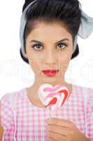 Serious black hair model holding a heart shaped lollipop