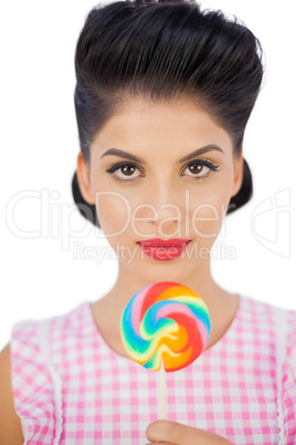 Unsmiling black hair model holding a colored lollipop