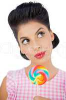 Wondering black hair model holding a colored lollipop