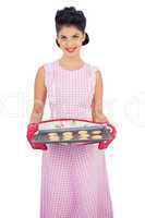 Pleased black hair model holding a baking tray of cookies