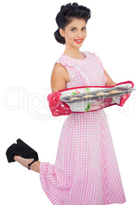 Content black hair model holding baking tray of cookies