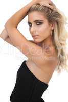 Attractive blonde model in black dress posing hands in the hair