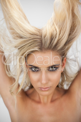 Charming blonde model in black dress posing holding her hair