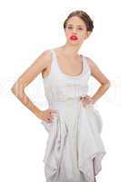Severe model in white dress posing hands on the hips