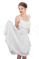 Gorgeous model in white dress posing holding her dress