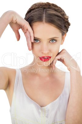 Smiling model in white dress posing touching her temple and her