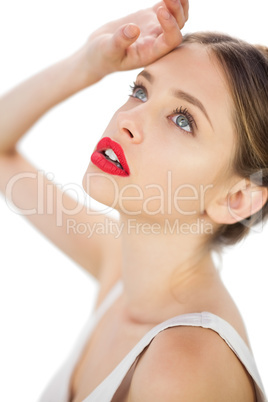 Elegant model in white dress posing with a hand on her forehead