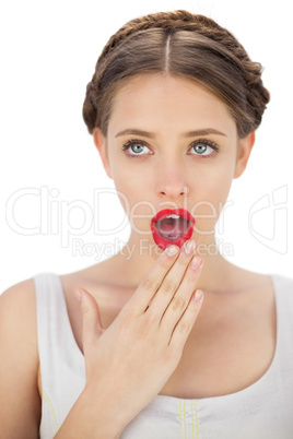 Amazed model in white dress posing covering her mouth