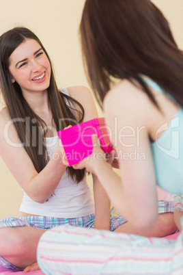 Happy girl in pajamas receiving a present from her friend