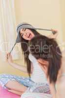 Funny pretty girl trying on a wool hat for her laughing friend