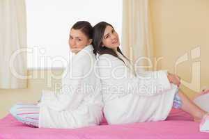 Two friends wearing bathrobes sitting back to back