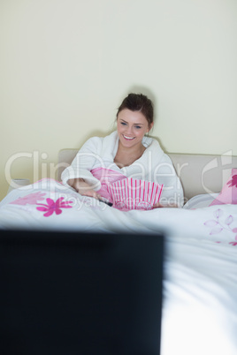 Laughing teen wearing bathrobe watching tv