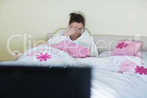 Pretty teen wearing bathrobe watching scary movie