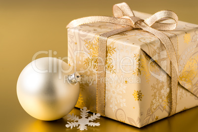 Christmas present and bauble on gold background